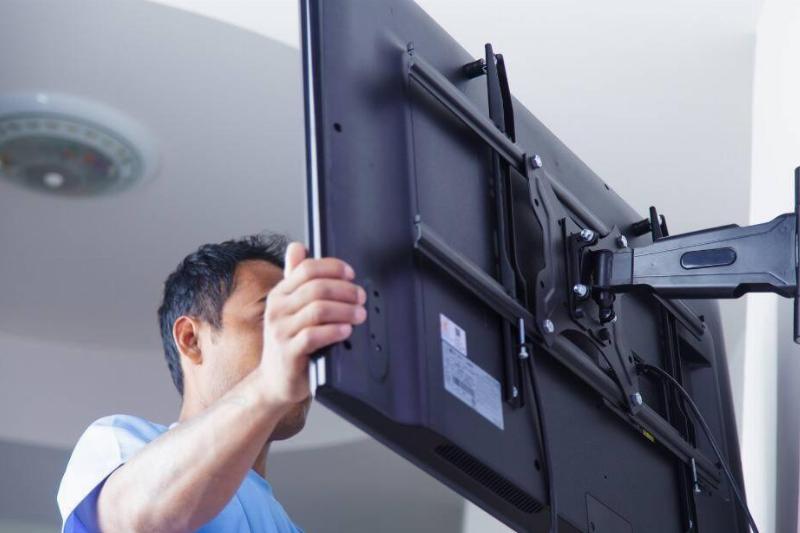 A man mounting a TV on a wall. 