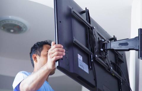 A man mounting a TV on a wall. 