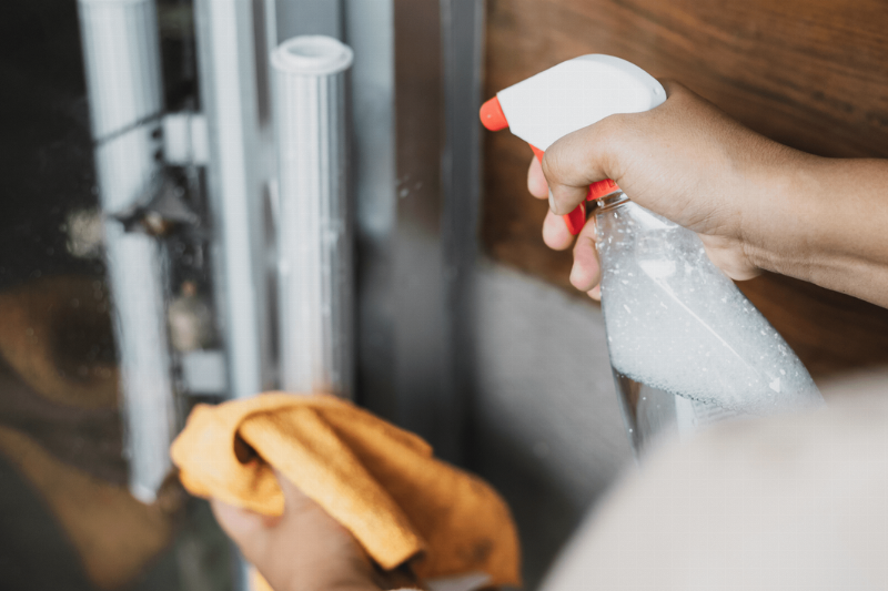 A person spraying cleaner on a surface. 