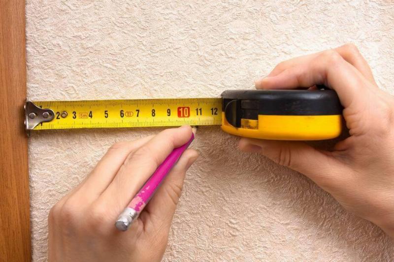 Marking a measurement on a wall with a pencil.