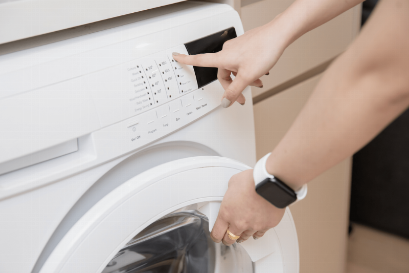 A person selecting settings on a washer.