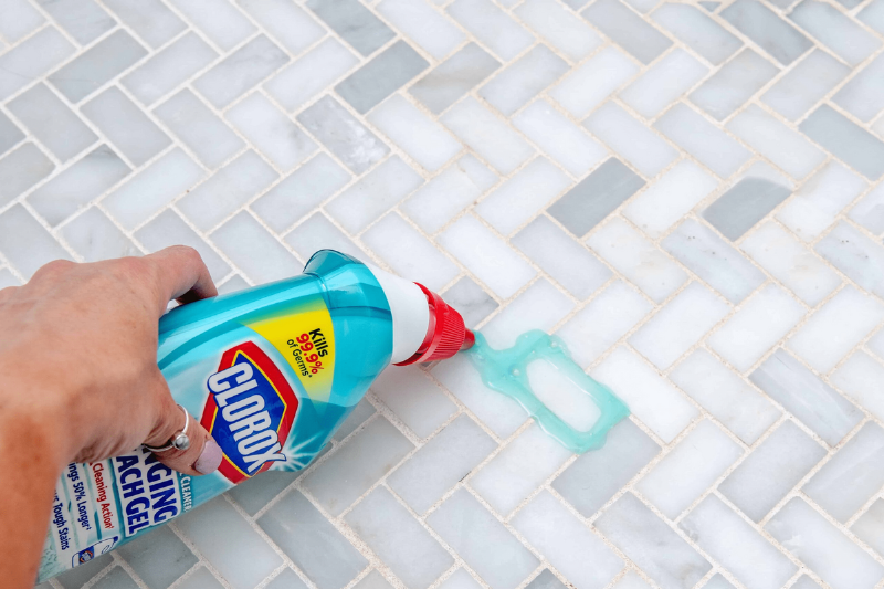 Pouring Clorox on tile grout.