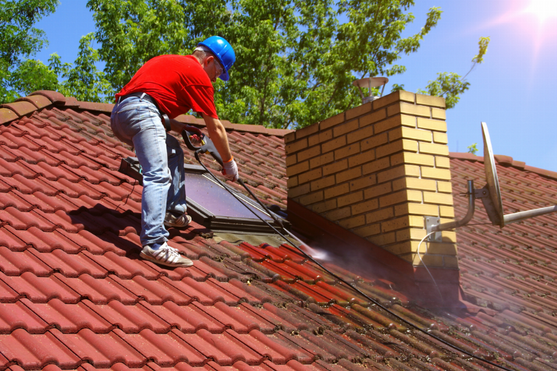 A person pressure washing a roof.