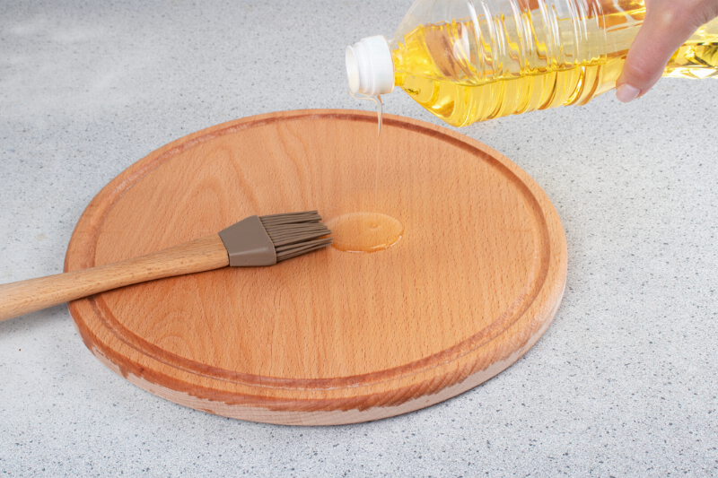Pouring oil on a wooden circular cutting board. 