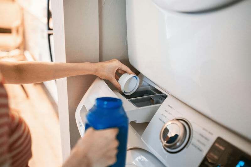 Person pouring detergent into machine.