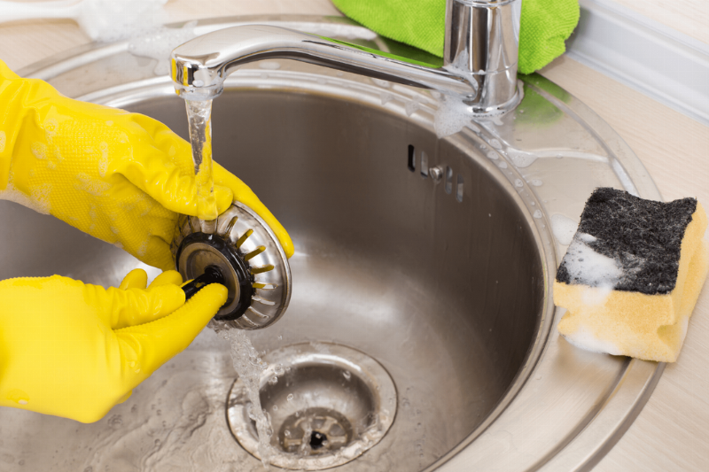 A person washing a sink filter.