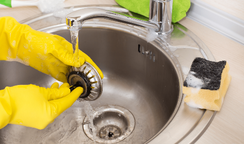 A person washing a sink filter.