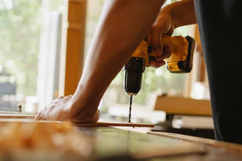A hand drilling into a piece of wood.