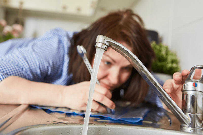 A woman fixing a faucet.