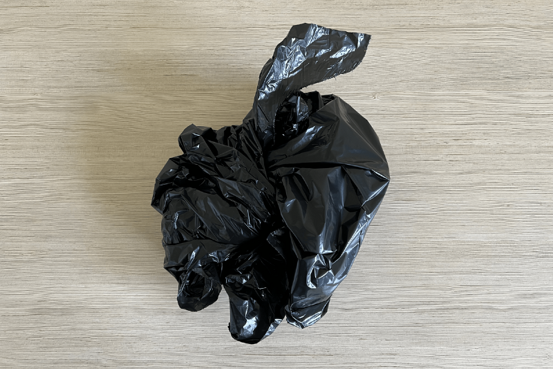 A black garbage bag wrapped up to keep all the craft mess inside. 