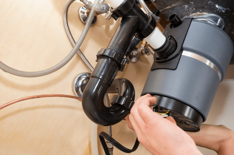 A hand fixing a jammed garbage disposal. 