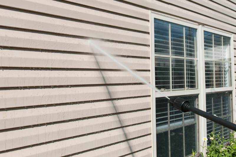 Pressure washing siding on a house. 