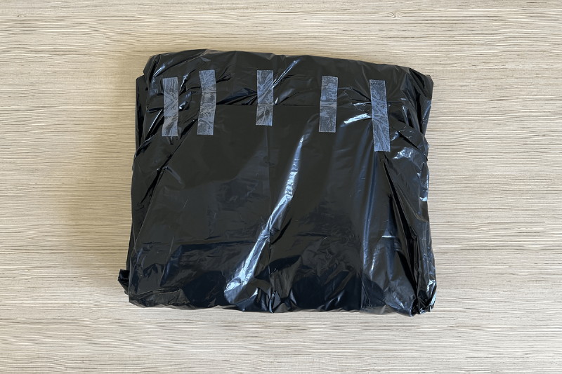 A black garbage bag filled with flyers and taped up.