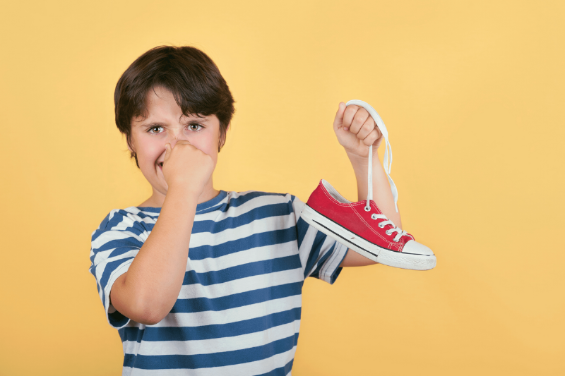 Boy holding his nose and a red shoe. 