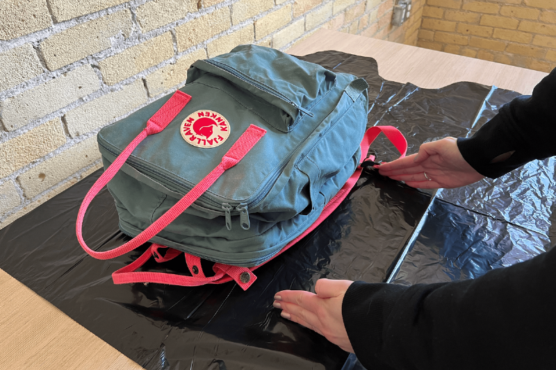 A backpack on a garbage bag on a table. 