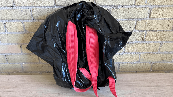 A backpack covered by a garbage bag. 