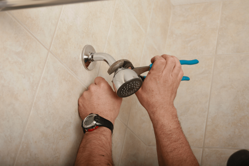 Hands using pliers to attach shower head. 