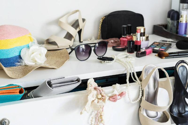 Cluttered accessories on top of a dresser. 