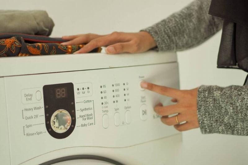 A person selecting the setting on a dryer. 