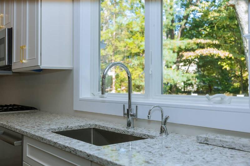 Kitchen with marble counters near a sink and window. 