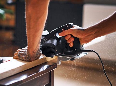 A person using a circular hand saw. 