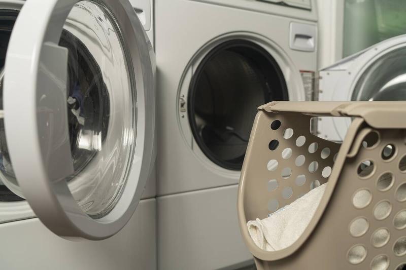 A laundry basket near an open dryer. 