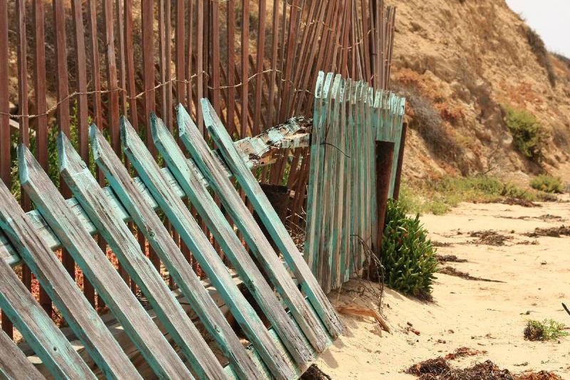 A broken piece of a green wooden fence. 