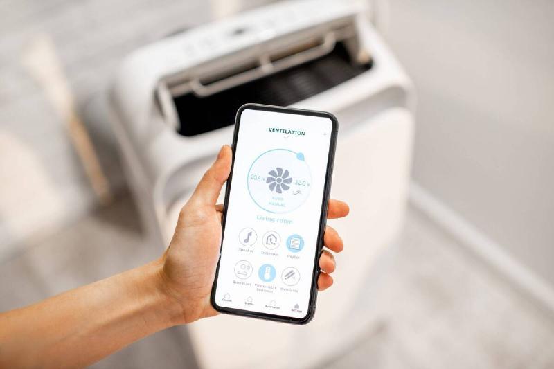 A hand holding a smart phone that controls the AC. 