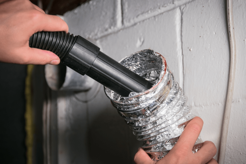 A person cleaning lint out of a dryer vent. 