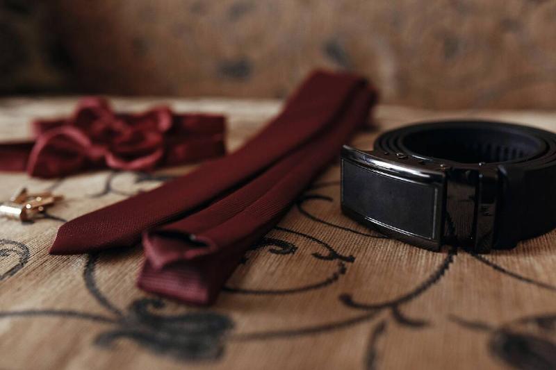 A belt and a tie on a wooden table. 
