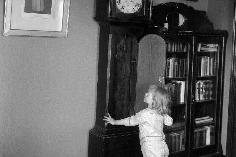 Girl (4-5) standing in front of grandfather clock