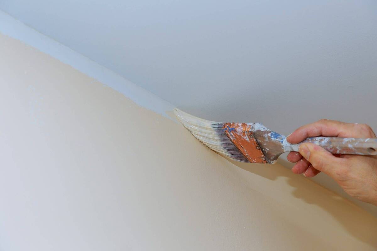 Painting the corner of a wall with a paintbrush. 