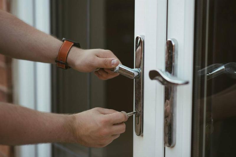 A person locking the front door of a house. 