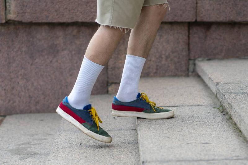 A man wearing white cotton tube socks in colorful sneakers. 
