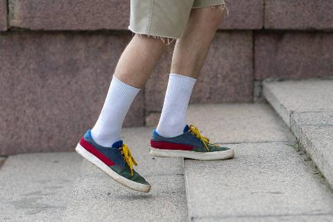 A man wearing white cotton tube socks in colorful sneakers. 