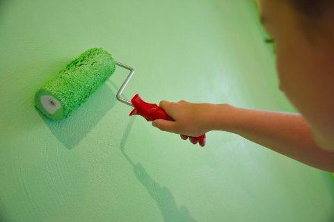 Rolling green paint on a wall. 
