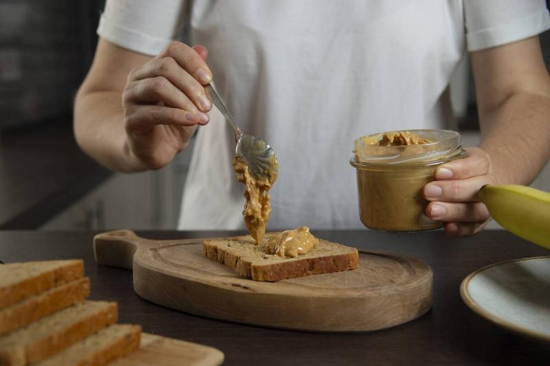 A person spreading peanut butter on bread. 