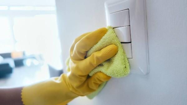 A hand wiping down light switches. 