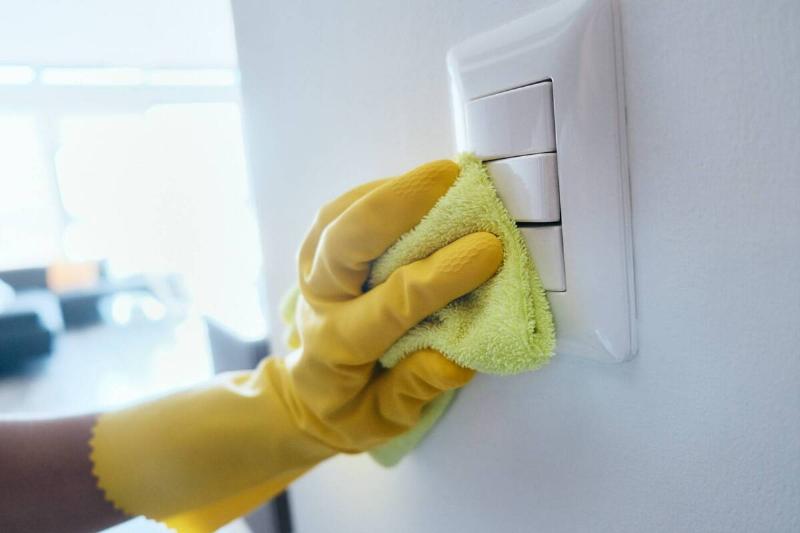 A hand wiping down light switches. 