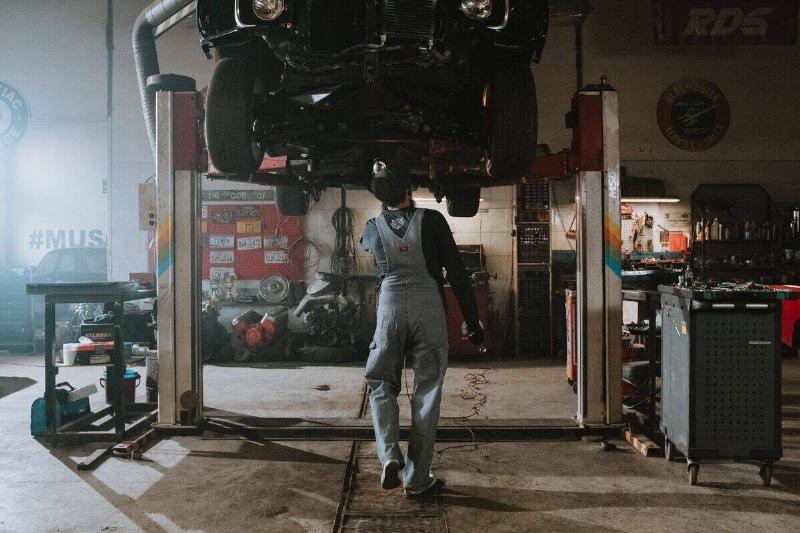 A mechanic fixing the bottom of a car. 