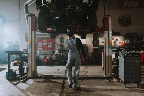 A mechanic fixing the bottom of a car. 