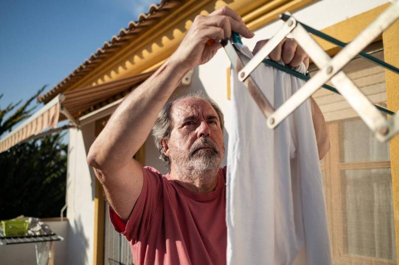 A man hanging laundry on a sunny day. 