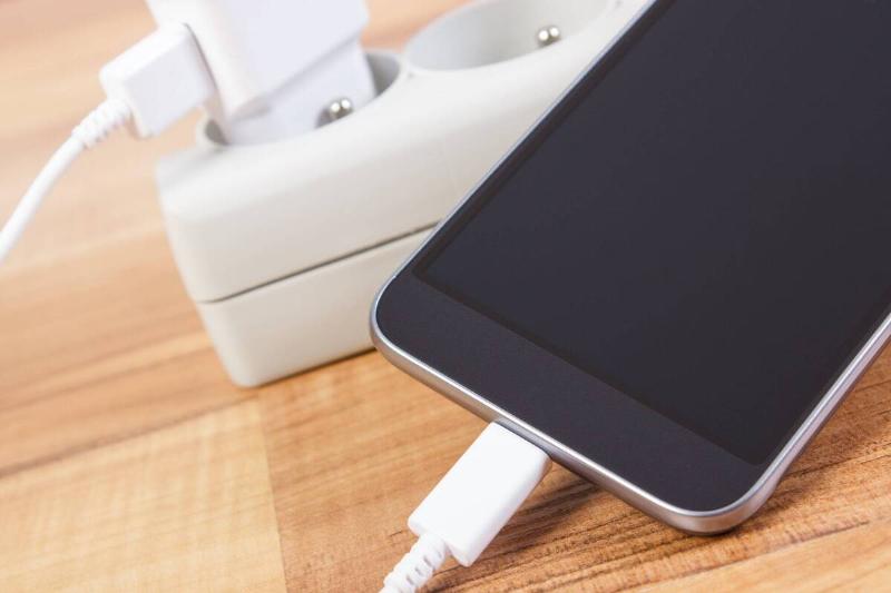 A smartphone with the charging cord plugged in. 