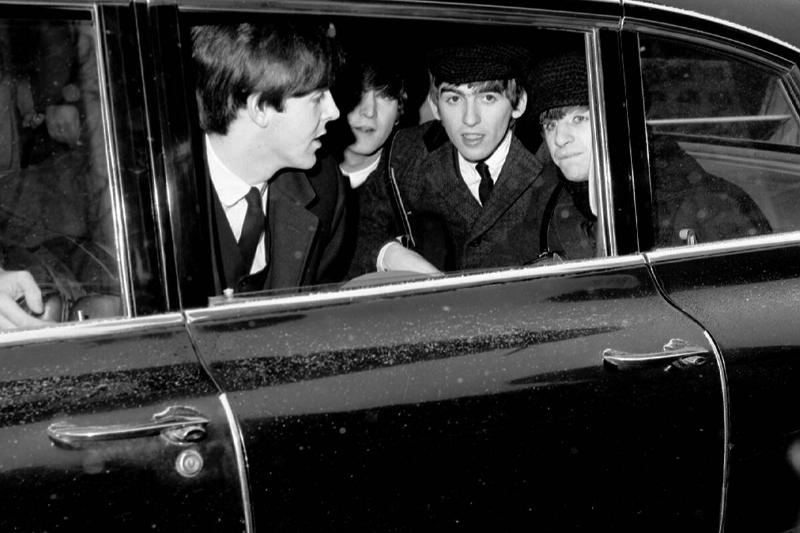 The Beatles huddle in back of limousine, en route to Penn St