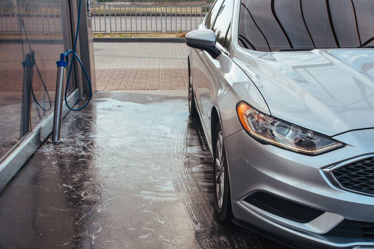 Silver car in a self-service car wash. 