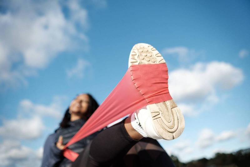 A woman using a resistance band around the sole of her shoe. 