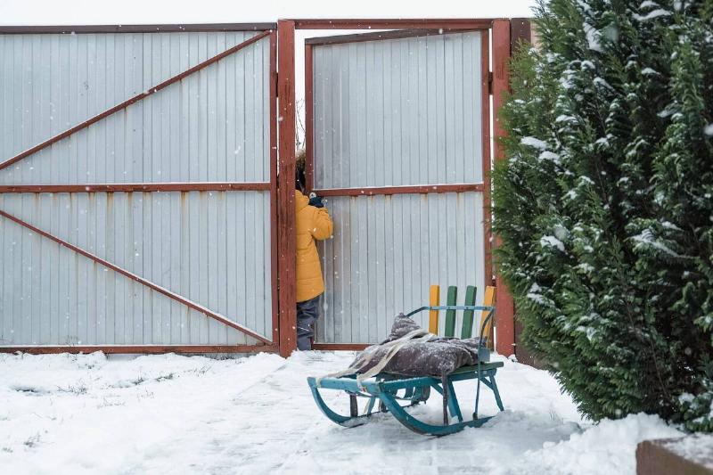 Someone opening the door of a fence in winter. 
