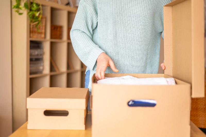 A person packing papers inside of a cardboard box. 