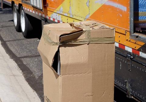 A cardboard box that has been damaged with the corner ripped open. 