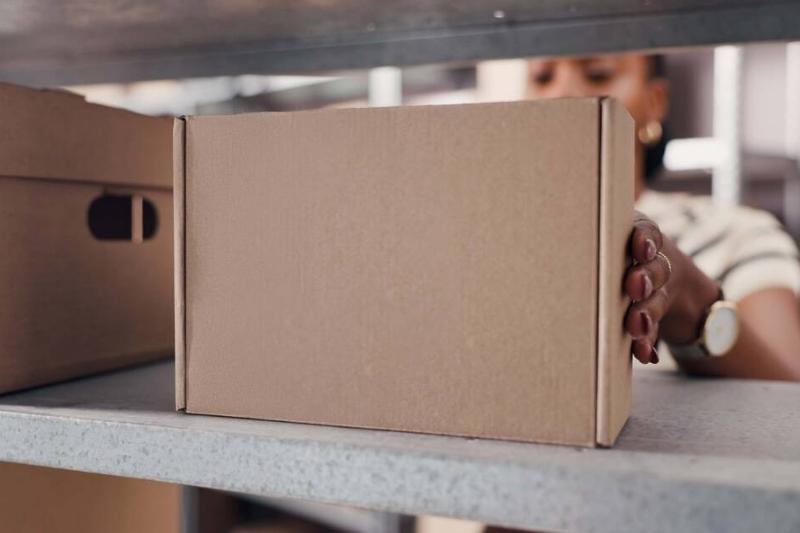 Hands putting. cardboard box on a shelf. 